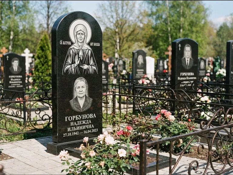 Памятник с гравировкой иконы: стела с арочным верхом и киотом под образ — гравировка образа Матроны Московской, гранитный цоколь с тёмной плиткой, работа «Ковалёв» в Белгороде