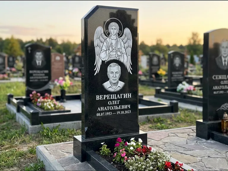 Памятник с гравировкой иконы: стела с резным навершием и нимбом в золоте — гравировка образа Спасителя, высокие разросшиеся туи полукругом, работа «Мельникова» в Белгороде