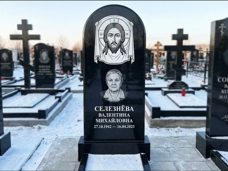 Памятник с гравировкой иконы: небольшая скромная одиночная стела с именной иконой — золочёный нимб на образе, аккуратный участок с газоном, работа «Ковалёв» в Белгороде