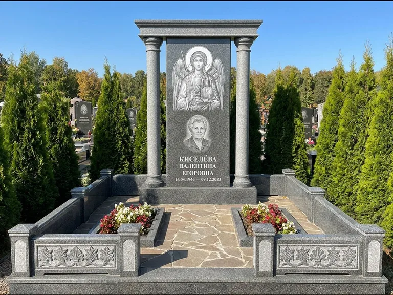 Памятник с гравировкой иконы: массивная стела с двускатным навершием-домиком — гравировка Николая Чудотворца, живая изгородь из туи, работа «Журавлёв» в Белгороде
