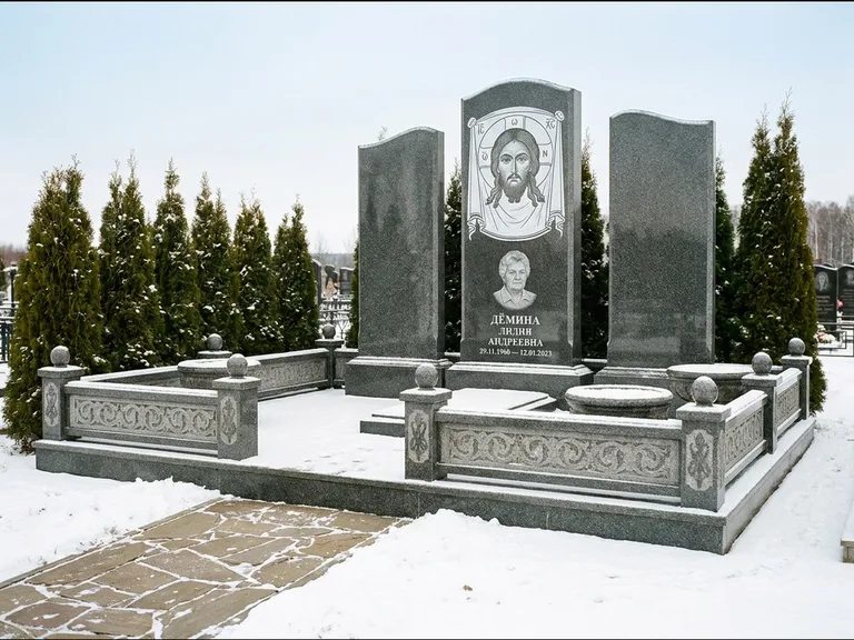 Памятник с гравировкой иконы: узкая вертикальная стела-пилон с ликом — икона в резной рамке-киоте, открытая лужайка без ограды, работа «Одинцов» в Белгороде