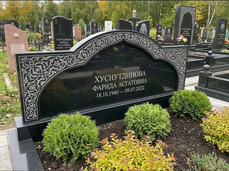 Мусульманский памятник: вытянутая горизонтальная семейная стела с аркой — белая гравировка силуэта мечети с минаретами, участок с декоративными кустами, работа «Зарипова» в Белгороде