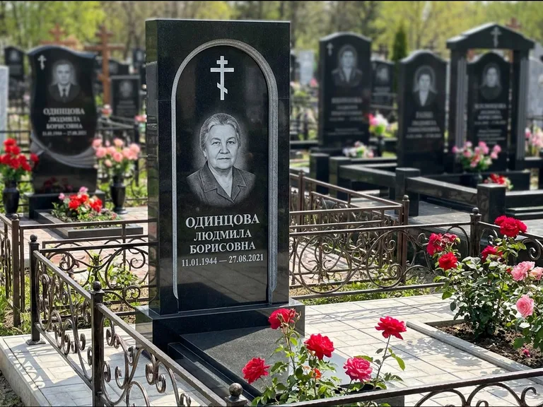 Памятник из чёрного гранита — скромная невысокая стела с крестом с терновым венцом, работа «Лаврентьева» в Белгороде