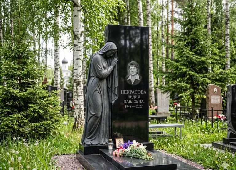 Гранитная фигура скорбящего мужчины у чёрной стелы в Белгороде
